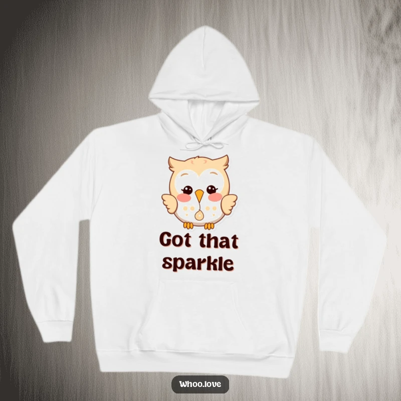 Funny hoodie featuring a happy owl with a playful glint, dropping a small, shiny object with a cheerful expression.