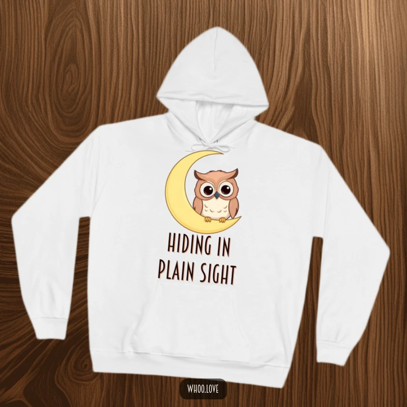 Funny hoodie showcasing a comical owl with big googly eyes peeking from behind a giant crescent moon, offering cozy laughs.